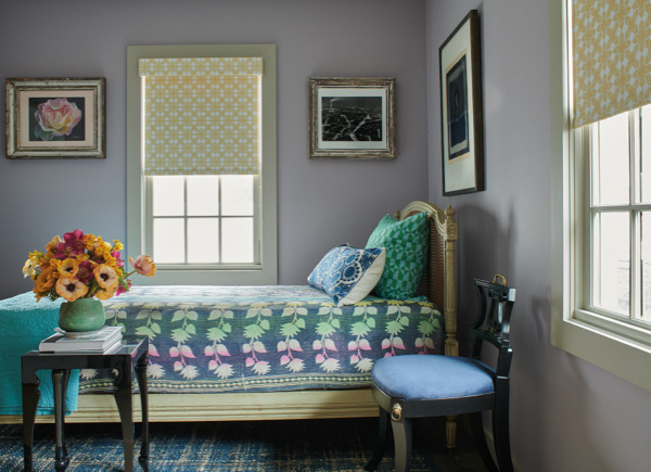 A colorful bedroom features lavendar walls and Blackout Roller Shades made of Sheila Bridges' Porringer in Mimosa