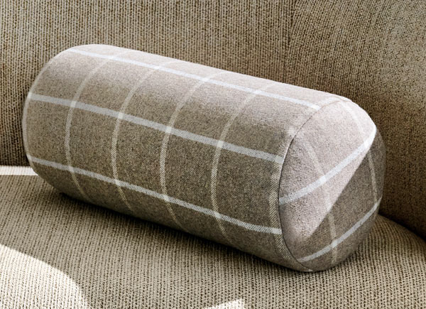 A sigular bolster pillow with a knife edge in material highland and color mica on a neutral colored couch