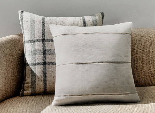 Two square pillows with knife edge seams positioned on a neutral couch