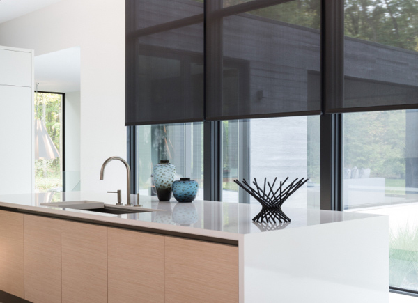Floor to ceiling windows featuring 3 percent solar shades hung in a kitchen with white walls and a large island with a sink