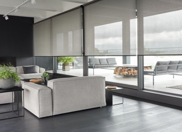 Solar Shades made of 5% Metallic in Zinc cover large floor-to-ceiling windows in an open grey living room