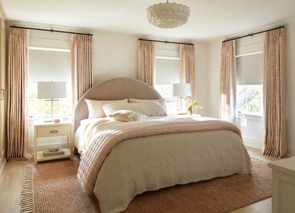 Windows featuring tailored pleat drapery in material chinoiserie and color blush in a pink and white bedroom with large bed