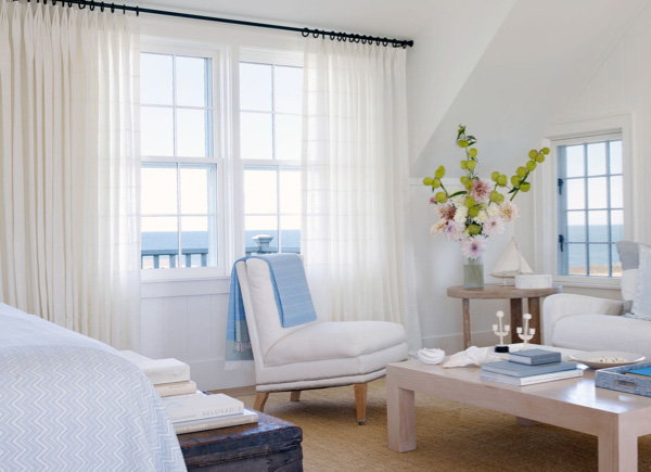 Large windows featuring tailored pleat drapery in sankaty stipe moon in a bedroom with an ocean view and white seating