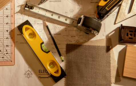 A table top with scattered measurement and installation tools along with plans and materials