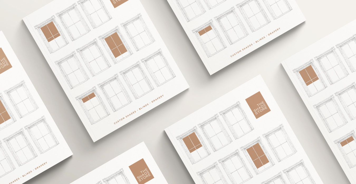 The Shade Store 2023 Lookbook with various windows in white with brown shades on the white cover featured on a white table.