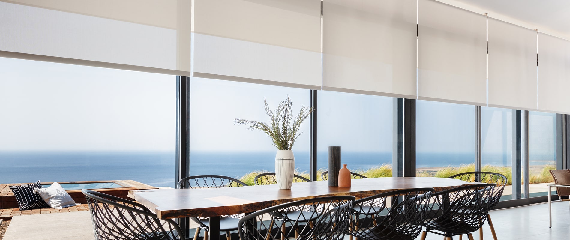 Full wall of windows in a large dining room with beach views featuring Solar Shades in 5% Grey fabric.