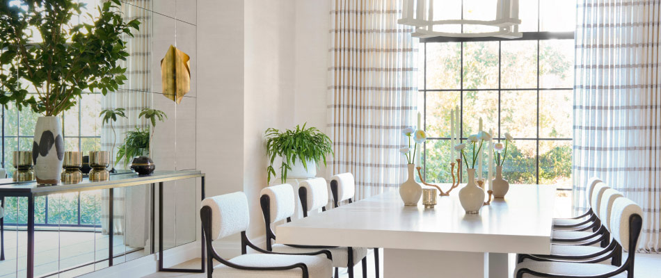 Tailored Pleat Drapery made of Victoria Hagan Lily in Silver hangs in a contemporary dining room with a white marble table