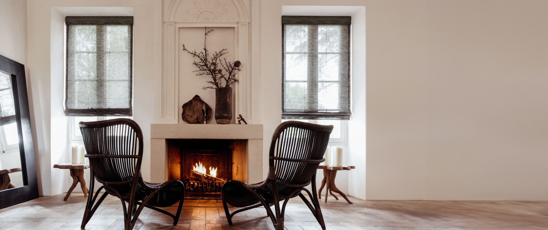 Cozy sitting area with fireplace flanked by windows dressed with waterfall woven wood shades in cafe grassweave material