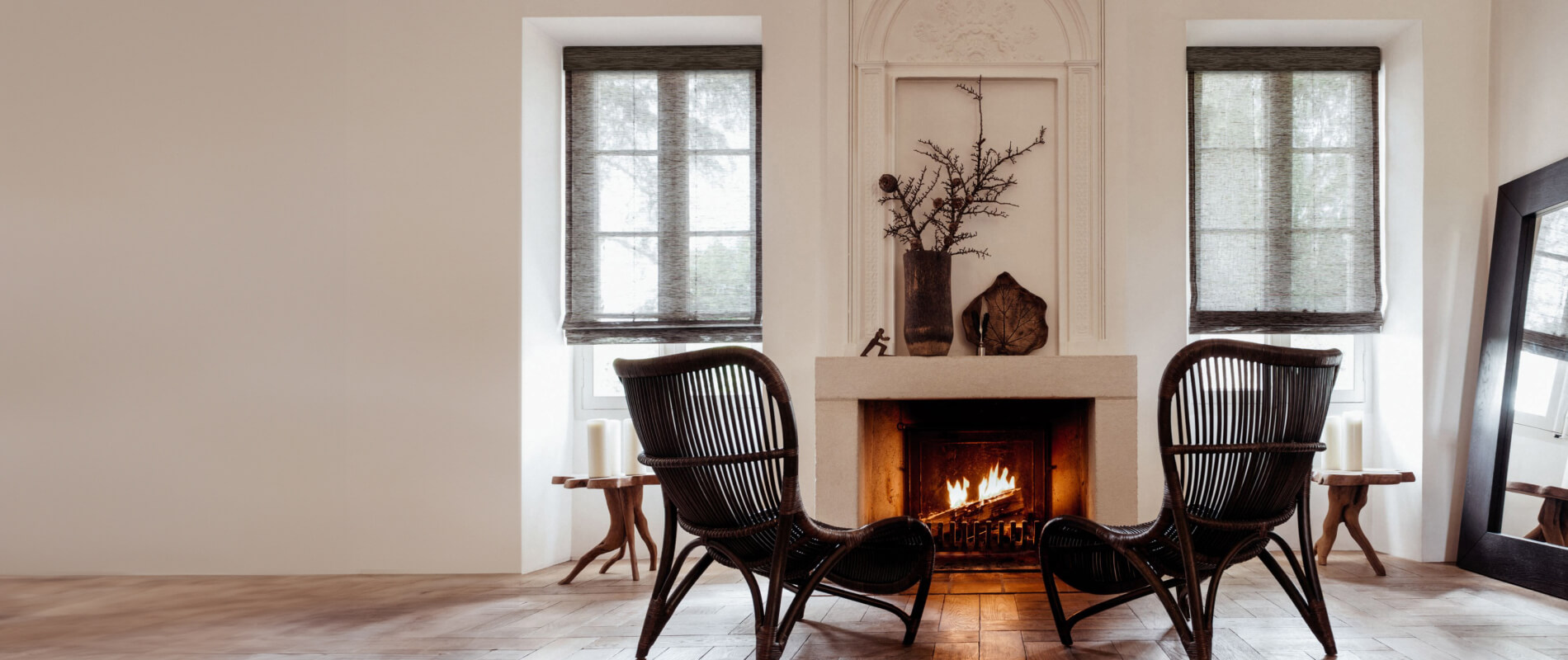 Cozy sitting area with fireplace flanked by windows dressed with waterfall woven wood shades in cafe grassweave material