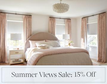 Blackout Drapery & Roller Shades darken a pink and white bedroom with sales messaging for Summer Views Sale: 15% Off