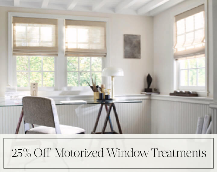 25% Off Motorized Window Treatments in black text over an image of Grassweave Cordless Woven Wood Shades in an office