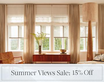 Layered shades & drapery add dimension to a living room with wood decor & sales messaging for Summer Views Sale: 15% Off