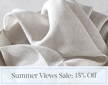 A swatch of Luxe Sheer Linen placed in a cream bowl on a white table top with sales messaging for Summer Views Sale: 15% Off
