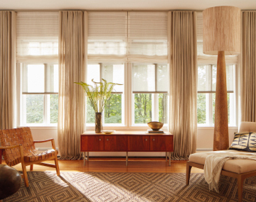 Layered Solar Shades, Flat Roman Shades & Ripple Fold Drapery in neutral fabrics add texture to a living room with wood decor