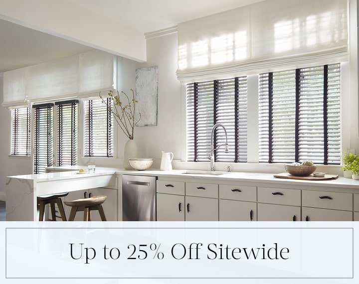 Up to 25% Off Sitewide in black text over an image of a kitchen with Flat Roman Shades and Wood Blinds.