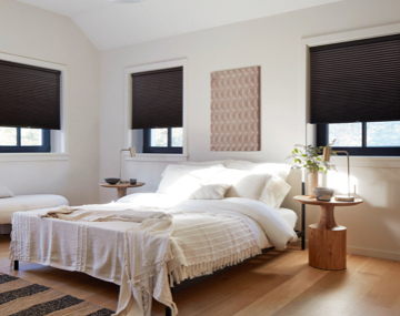 Blackout Cellular Shades in Midnight hung over black framed windows in an all white bedroom