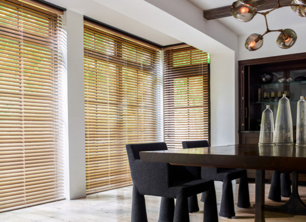 2 Inch Champagne Metal Blinds hung over floor to ceiling windows in a dining room with a large table with black chairs 