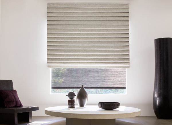 Large window with Pleated Roman Shade in a room with a short white table and black decor