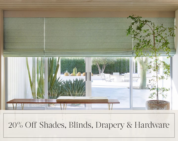 20% Off Shades, Blinds, Drapery & Hardware in black text over an image of living room windows with sage green Roman Shades.