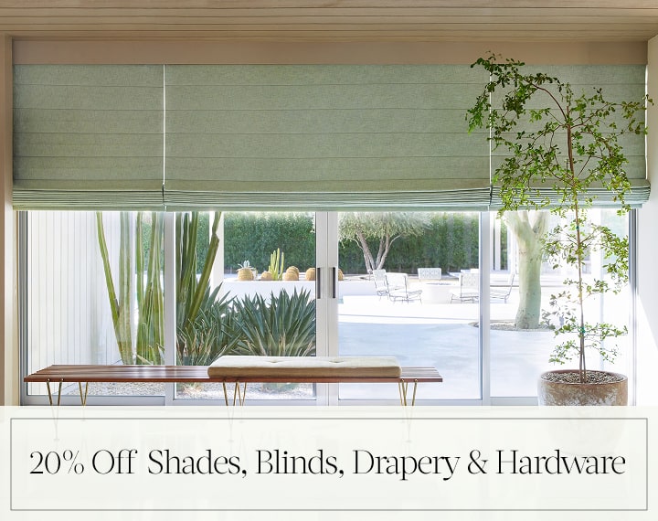 20% Off Shades, Blinds, Drapery & Hardware in black text over an image of living room windows with sage green Roman Shades.
