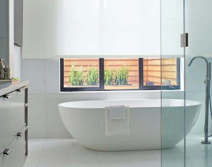 Modern Barthroom with freestanding bathtub with large window fearuting Solar Shade in 1 percent material in the color White