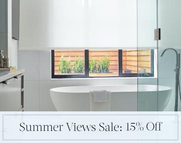 Solar Shades hang in a white bathroom with a freestanding tub with overlaid sales messaging for Summer Views Sale: 15% Off