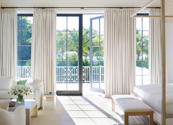 Tailored Pleat Drapery featured over floor to ceiling patio doors in a bedroom with modern furniture and neutral decor