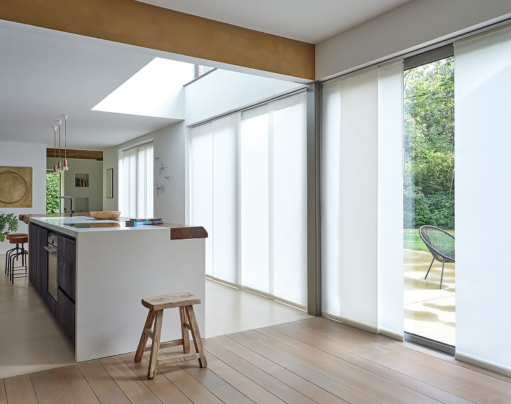 A kitchen with wood flooring and Panel Track Vertical Blinds on patio doors.