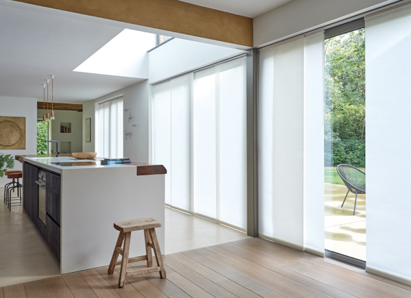 Large patio doors featuring panel track vertical blinds hung in an open kitchen with a large white centered island