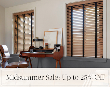 Oak Wood Blinds hang in an office with a wood desk & leather chair with overlaid text, Midsummer Sale: Up to 25% off