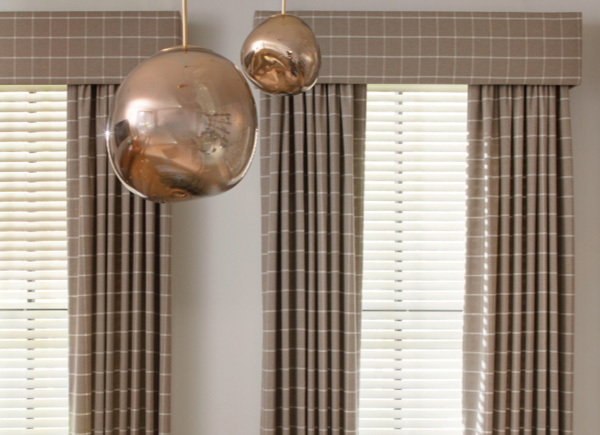 Drapery with a matching cornice, both made of Highland in Mica layer with blinds on windows behind metal light fixtures