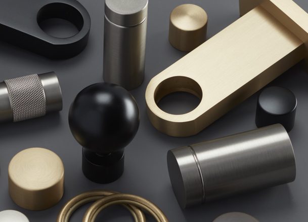 The components for the brass drapery hardware set Kingston lay artistically on a black table for dramatic effect
