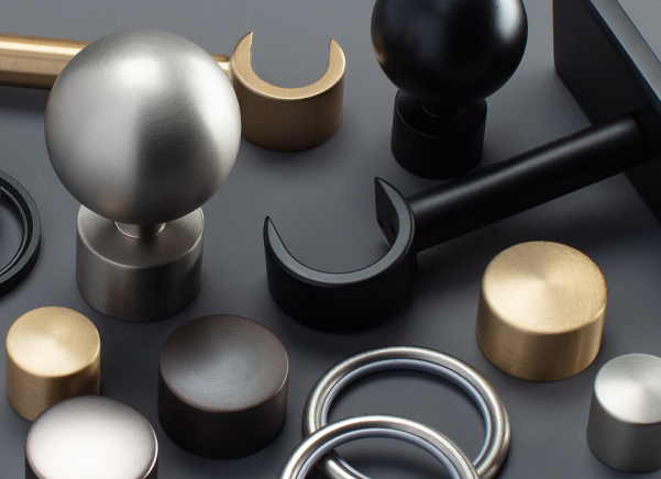 The components for the brass drapery hardware set Saratoga lay artistically on a black table for dramatic effect
