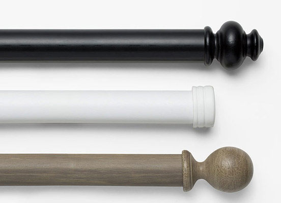 Three drapery hardware options in various Royal Wood finishes laid out on a white table top