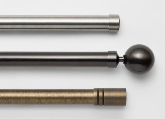 Three drapery hardware options in various Steel finishes laid out on a white table top
